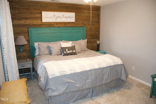 bedroom with baseboards, carpet floors, wooden walls, and visible vents