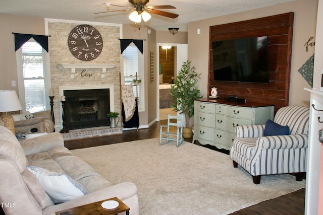 living area featuring ceiling fan, a textured ceiling, wood finished floors, and a fireplace