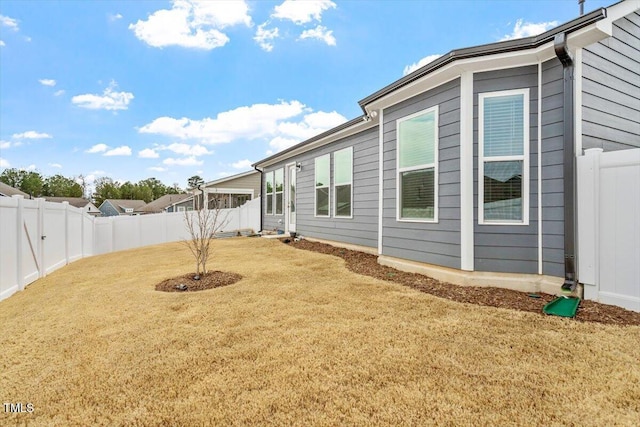 view of side of home featuring a fenced backyard and a yard