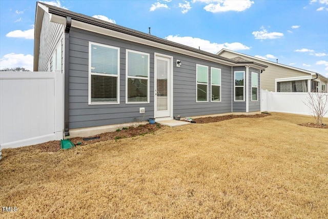 rear view of property featuring a lawn and fence