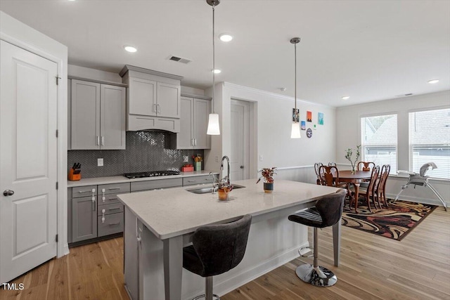 kitchen with gas cooktop, visible vents, light wood-style flooring, a sink, and gray cabinetry