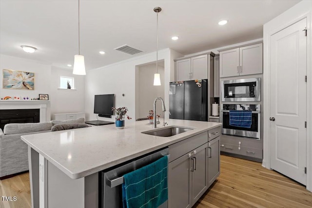 kitchen with gray cabinets, appliances with stainless steel finishes, a fireplace, and a sink