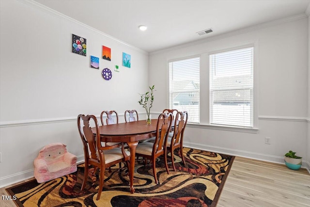 dining area featuring visible vents, crown molding, baseboards, and wood finished floors