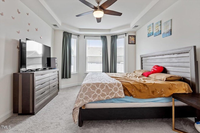 bedroom with baseboards, visible vents, a raised ceiling, and light carpet