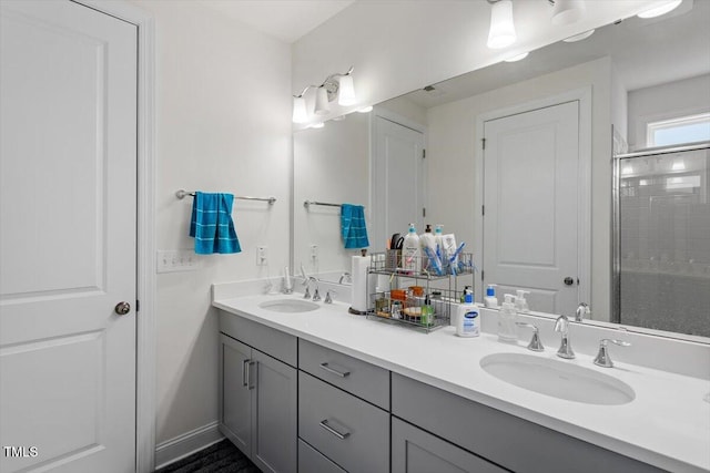 bathroom with double vanity, a tile shower, and a sink