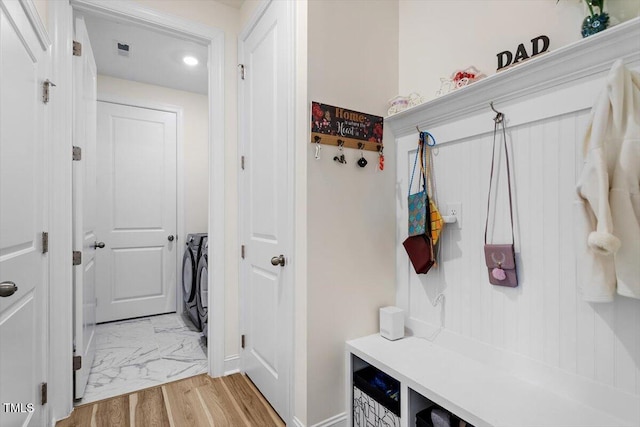 mudroom with visible vents, light wood finished floors, and washing machine and clothes dryer