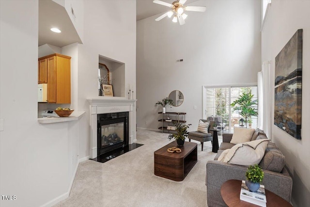 living area featuring a fireplace with flush hearth, baseboards, a towering ceiling, and carpet floors