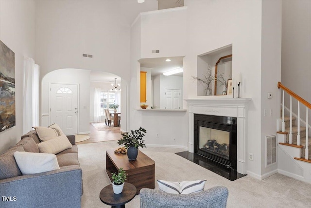 living area with stairway, carpet flooring, visible vents, and a fireplace with flush hearth