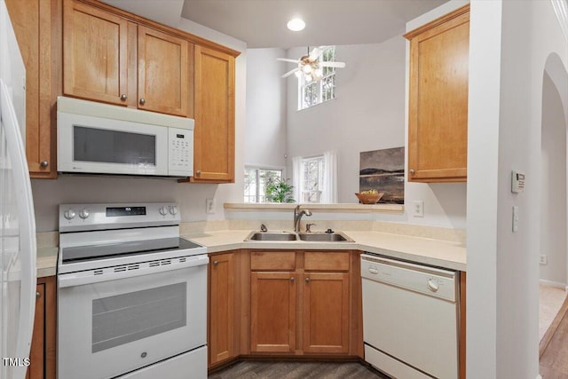 kitchen featuring white appliances, arched walkways, ceiling fan, a sink, and light countertops