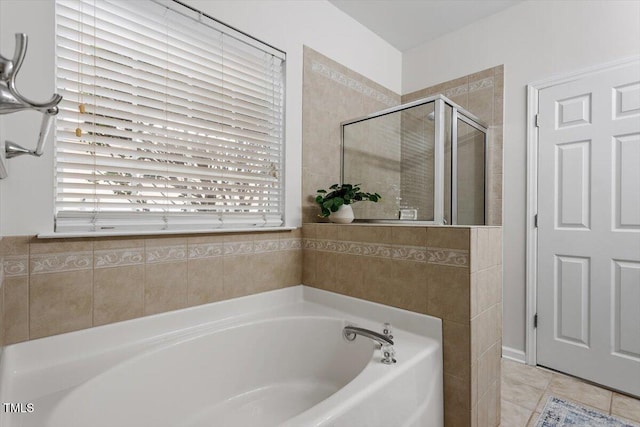 bathroom featuring tile patterned flooring, a bath, and a stall shower