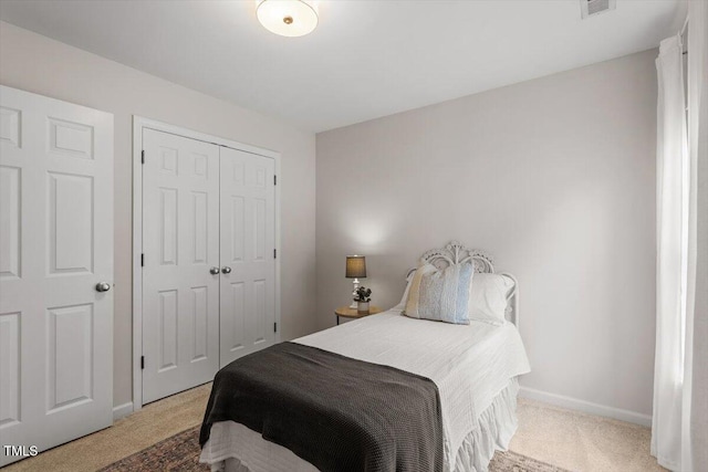 bedroom with baseboards, a closet, and light carpet