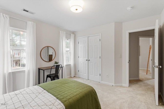 bedroom with visible vents, baseboards, light colored carpet, and a closet