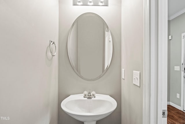 bathroom with ornamental molding, wood finished floors, baseboards, and a sink