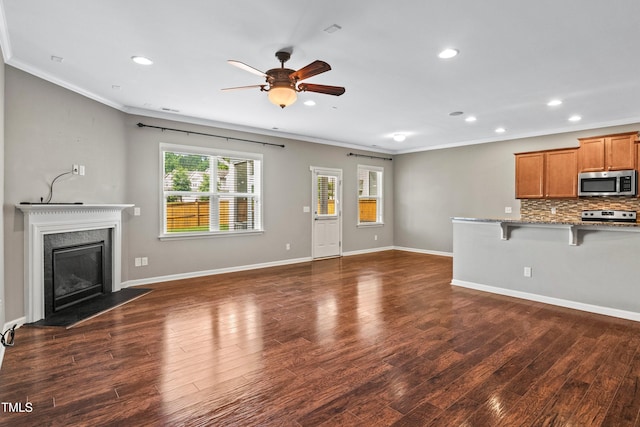 unfurnished living room with recessed lighting, crown molding, a premium fireplace, baseboards, and dark wood-style flooring