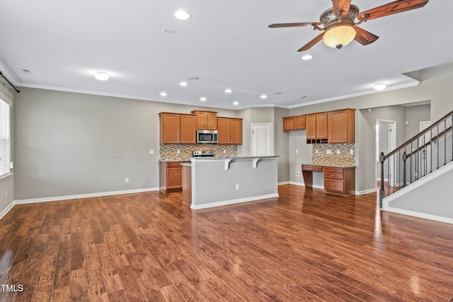 kitchen with baseboards, ornamental molding, dark wood-type flooring, appliances with stainless steel finishes, and brown cabinets