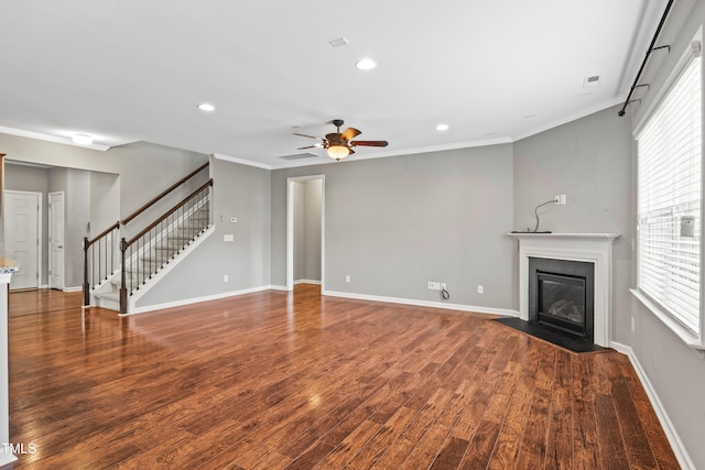 unfurnished living room with stairway, a fireplace with flush hearth, wood finished floors, and crown molding