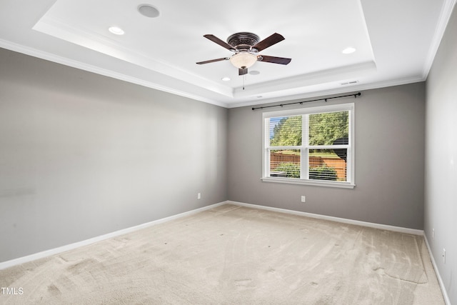 unfurnished room featuring a tray ceiling, baseboards, and light carpet