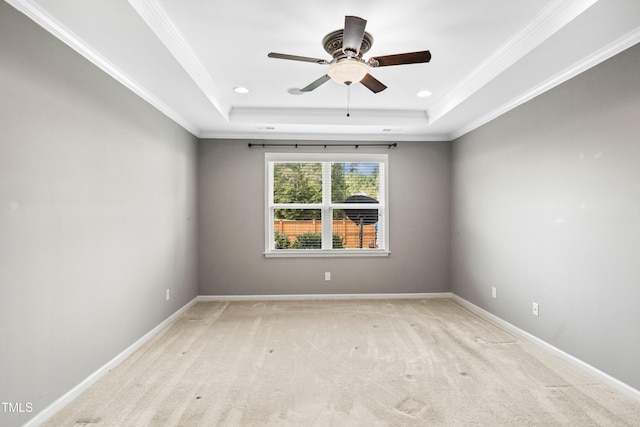 unfurnished room featuring a raised ceiling, light colored carpet, and ornamental molding