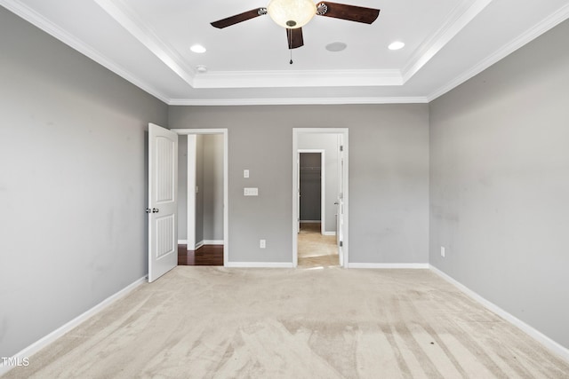 unfurnished bedroom featuring baseboards, recessed lighting, ornamental molding, a raised ceiling, and light colored carpet