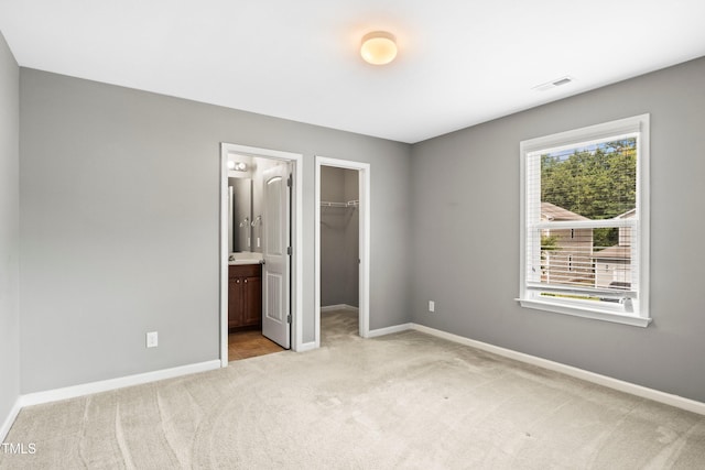 unfurnished bedroom featuring a spacious closet, visible vents, baseboards, carpet, and a closet