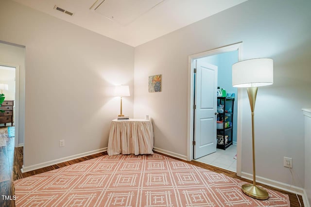 unfurnished room featuring visible vents, baseboards, attic access, and wood finished floors