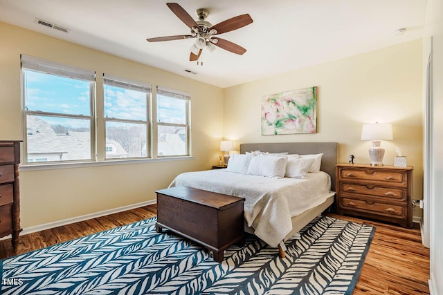 bedroom with wood finished floors, visible vents, and baseboards