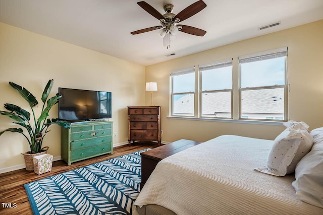 bedroom with visible vents, baseboards, and wood finished floors