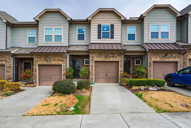 townhome / multi-family property featuring a standing seam roof, concrete driveway, an attached garage, and stone siding