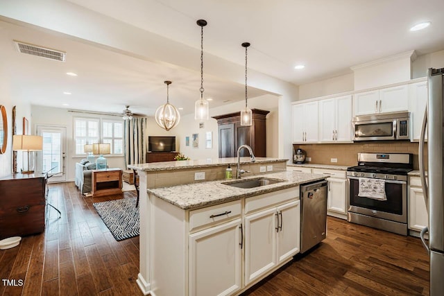 kitchen with visible vents, an island with sink, a sink, open floor plan, and stainless steel appliances