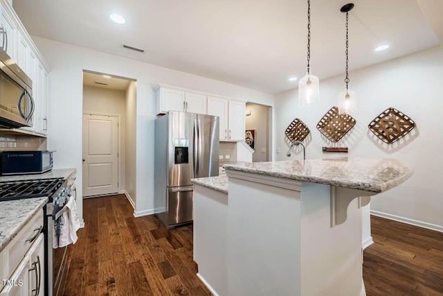 kitchen with visible vents, a kitchen island, dark wood-type flooring, appliances with stainless steel finishes, and white cabinets