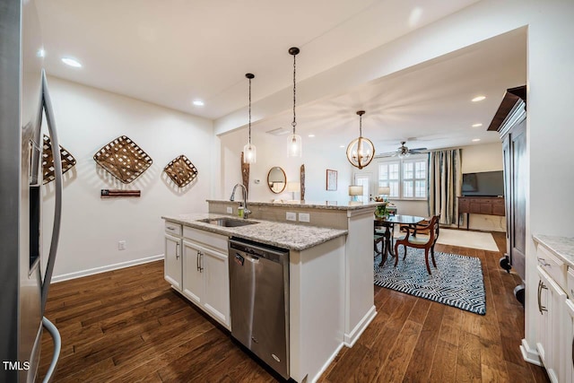 kitchen with a center island with sink, a sink, dark wood finished floors, white cabinetry, and appliances with stainless steel finishes