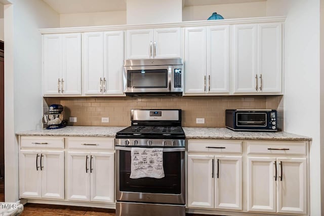 kitchen with stainless steel appliances, white cabinetry, backsplash, and a toaster