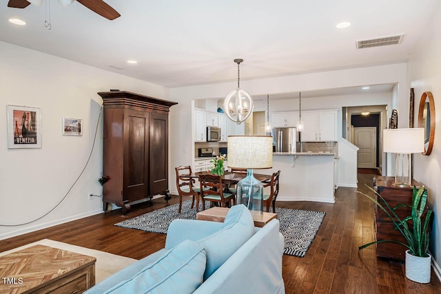 living area with recessed lighting, visible vents, dark wood-type flooring, and ceiling fan with notable chandelier