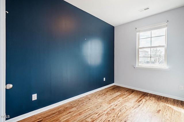 spare room featuring visible vents, baseboards, and wood finished floors