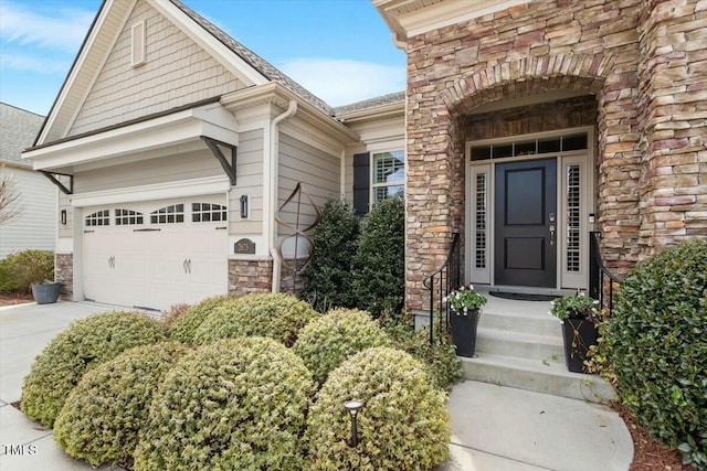 entrance to property with a garage, stone siding, and driveway