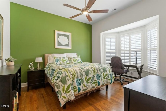 bedroom featuring visible vents, baseboards, ceiling fan, and wood finished floors