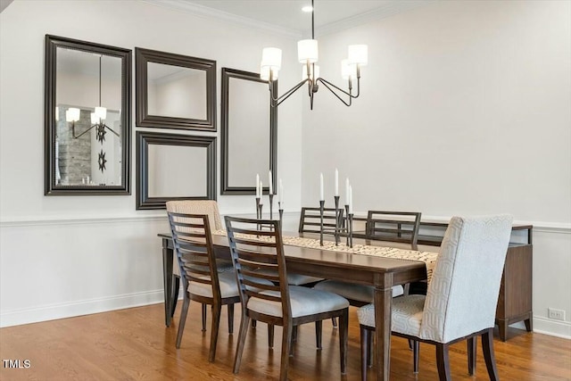 dining room featuring an inviting chandelier, crown molding, wood finished floors, and baseboards