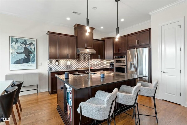 kitchen featuring under cabinet range hood, a sink, stainless steel appliances, light wood finished floors, and dark brown cabinets