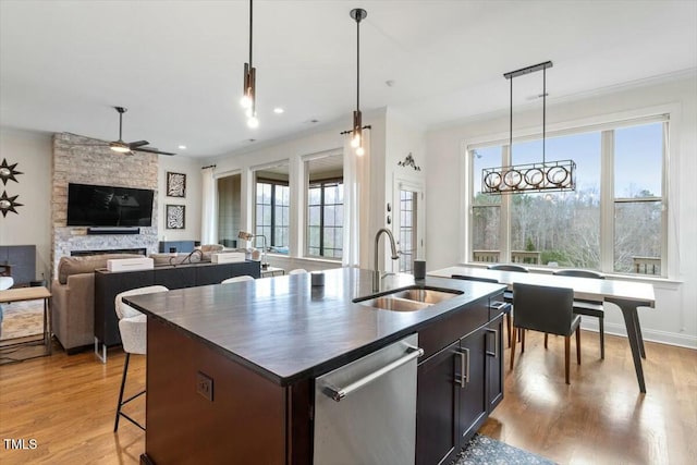 kitchen with a sink, stainless steel dishwasher, dark countertops, and ornamental molding