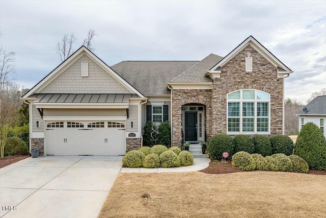 view of front facade featuring a shingled roof, concrete driveway, stone siding, an attached garage, and a standing seam roof