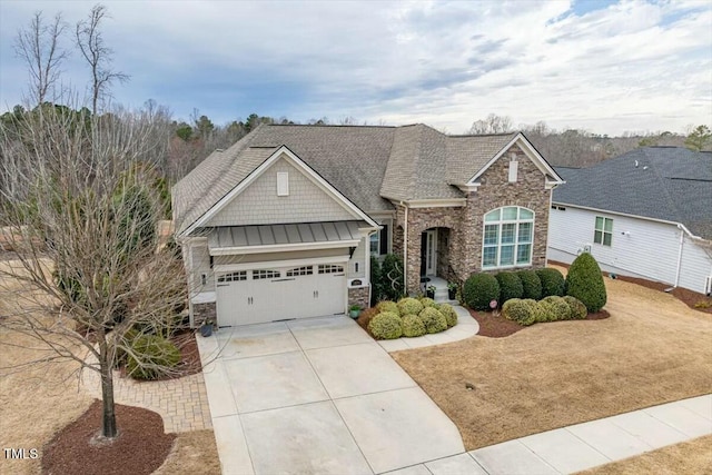 craftsman-style home with metal roof, driveway, stone siding, an attached garage, and a standing seam roof