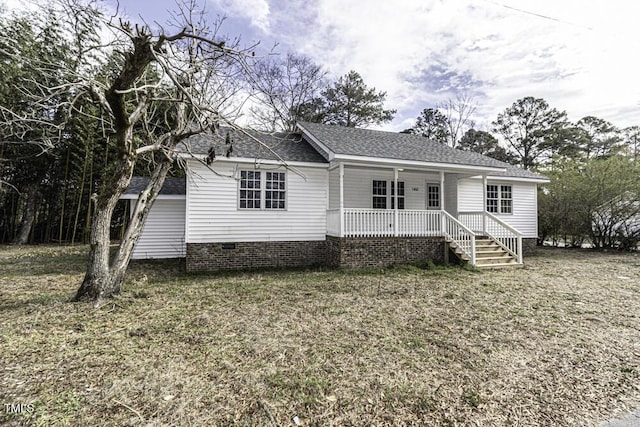 view of front of home with a shingled roof, a front yard, covered porch, and crawl space