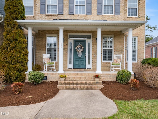 entrance to property with brick siding and a porch