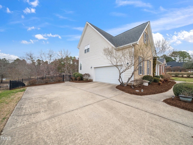 view of home's exterior featuring driveway, a garage, and fence