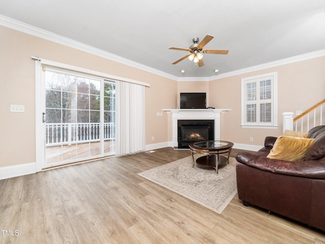 living area with crown molding, a lit fireplace, and wood finished floors