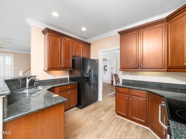 kitchen featuring a sink, ornamental molding, light wood-style floors, and black fridge