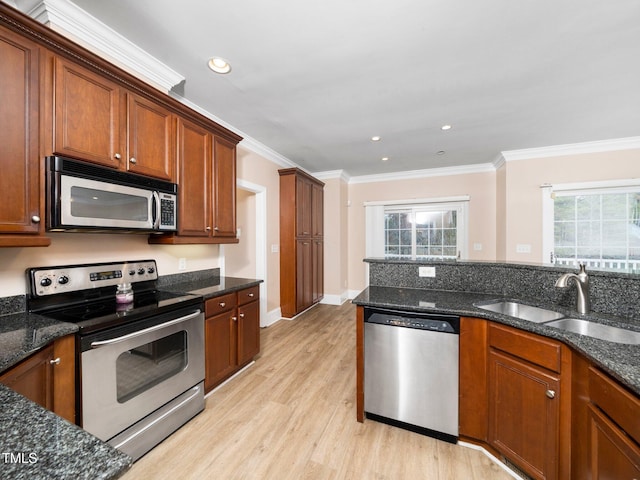 kitchen with a sink, stainless steel appliances, light wood-style flooring, and ornamental molding