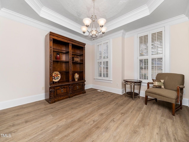 sitting room featuring light wood finished floors, an inviting chandelier, baseboards, and a tray ceiling