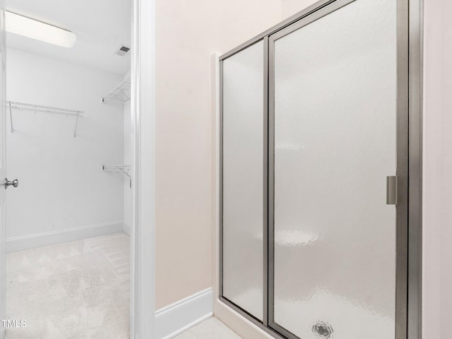 bathroom with visible vents, a spacious closet, baseboards, and a stall shower