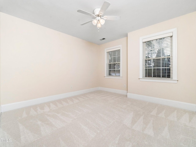 carpeted spare room with visible vents, ceiling fan, and baseboards